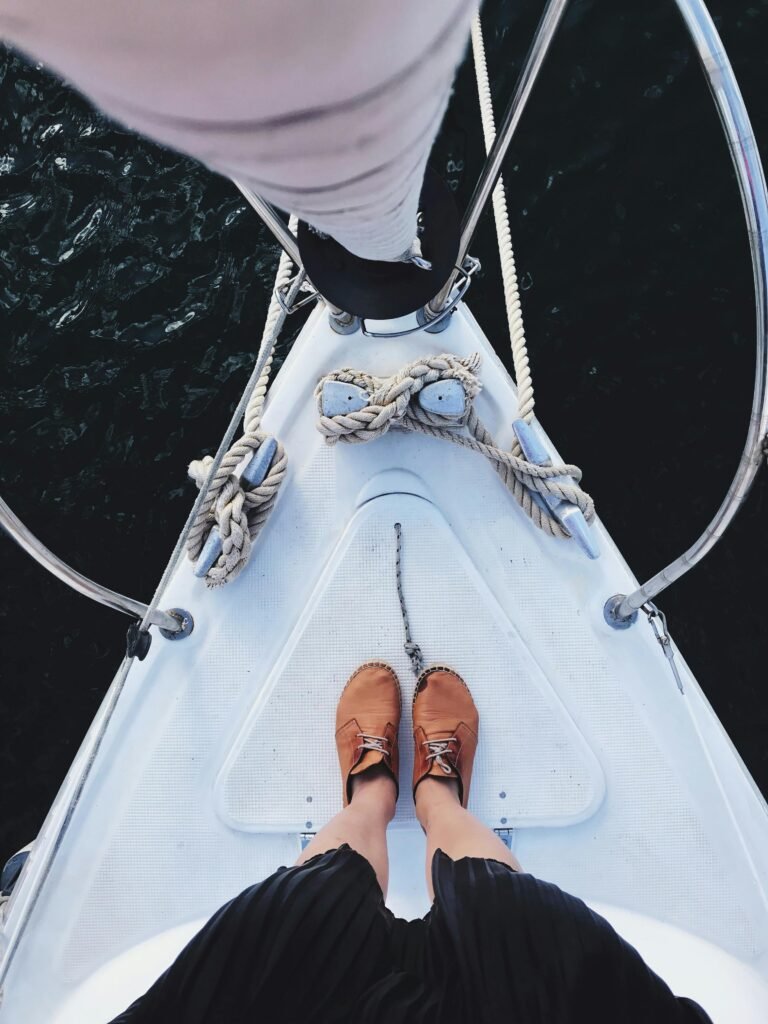 Person on a sailboat with moccasins contemplating becoming a competent crew.